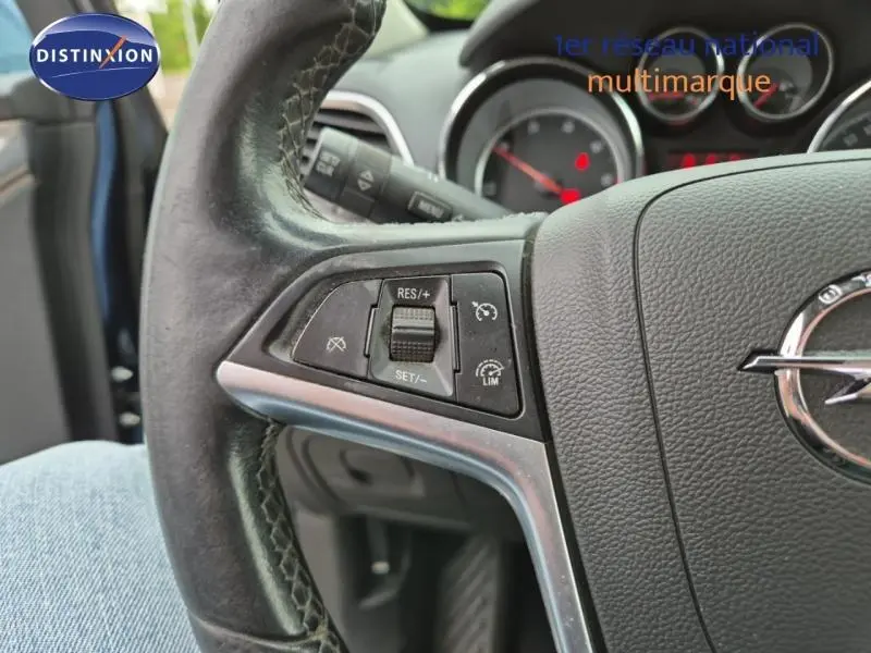 Gros plan sur le volant cuir de l'Opel Mokka bleu outremer, avec commandes de régulateur de vitesse visibles à gauche.