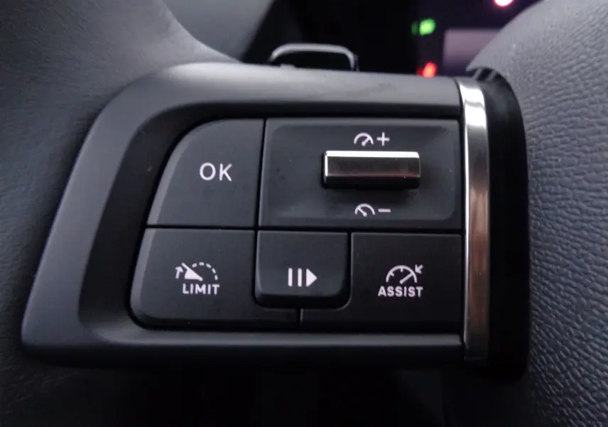 Gros plan sur les commandes au volant côté gauche d'une Citroën C5 X noire, avec boutons de régulateur et limiteur de vitesse.