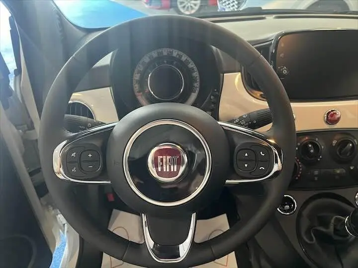 Vue rapprochée du volant noir de la Fiat 500 2023 avec tableau de bord blanc et écran tactile à droite