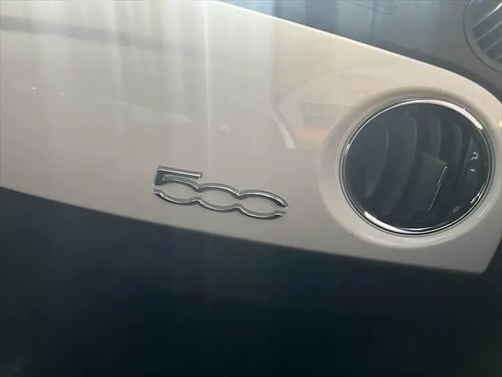 Gros plan sur le tableau de bord blanc de la Fiat 500 avec la sortie d'air ronde chromée et le logo 500 chromé.