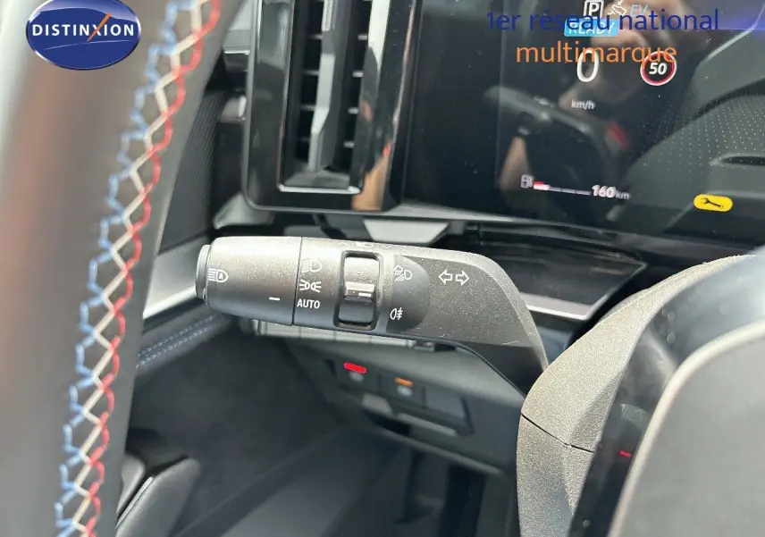 Gros plan sur la commande des feux et clignotants à gauche du volant dans l'habitacle du Renault Austral bleu.