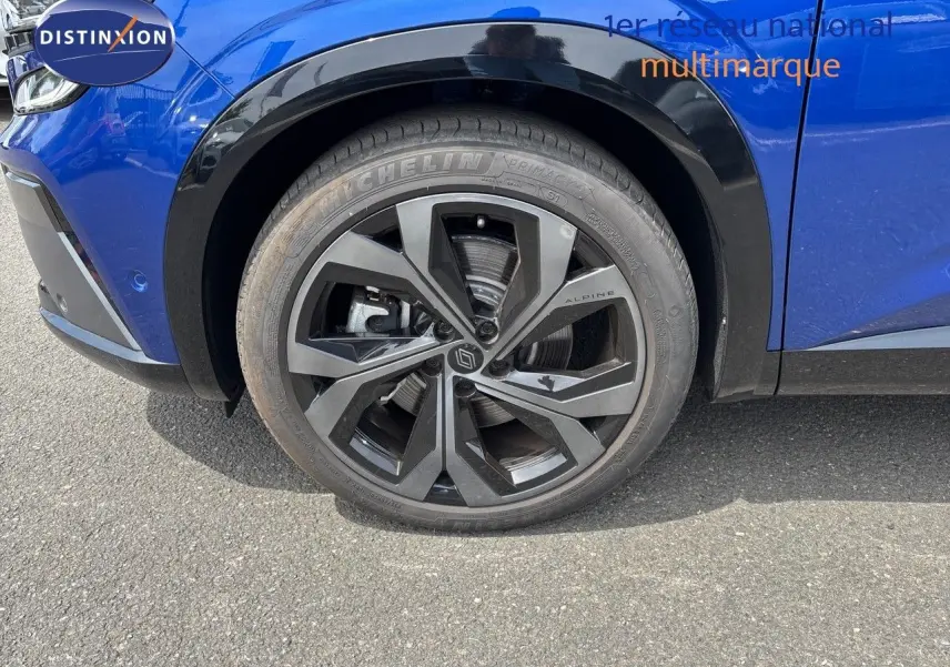 Gros plan sur la roue avant gauche du Renault Austral bleu Iron Metal avec jante noire Alpine et pneus Michelin.