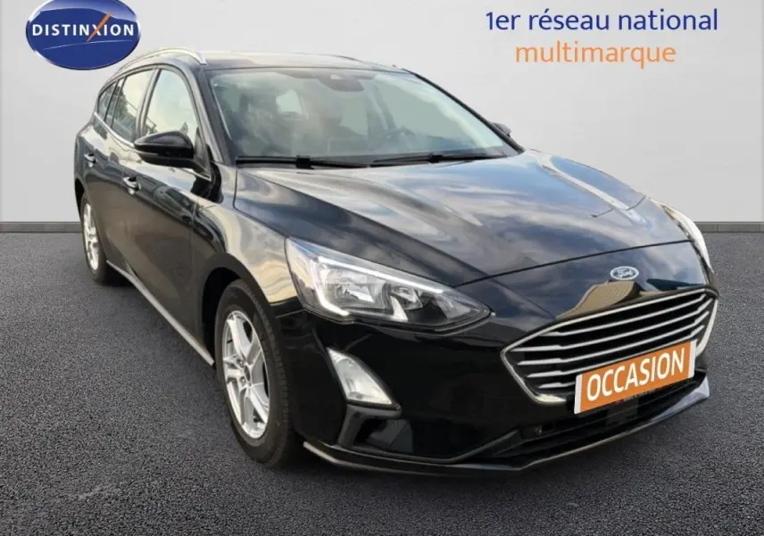 Ford Focus SW noire vue en 3/4 avant droit avec barres de toit et jantes alliage 16 pouces.