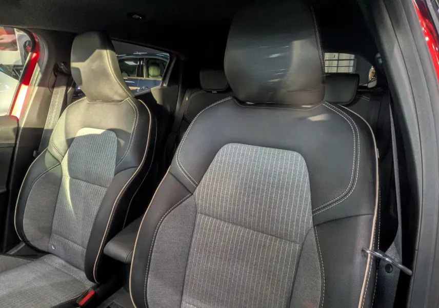 Vue rapprochée des sièges avant en cuir noir et tissu gris de la Renault Clio V Rouge Flamme, version ECO-100 CH TECHNO.