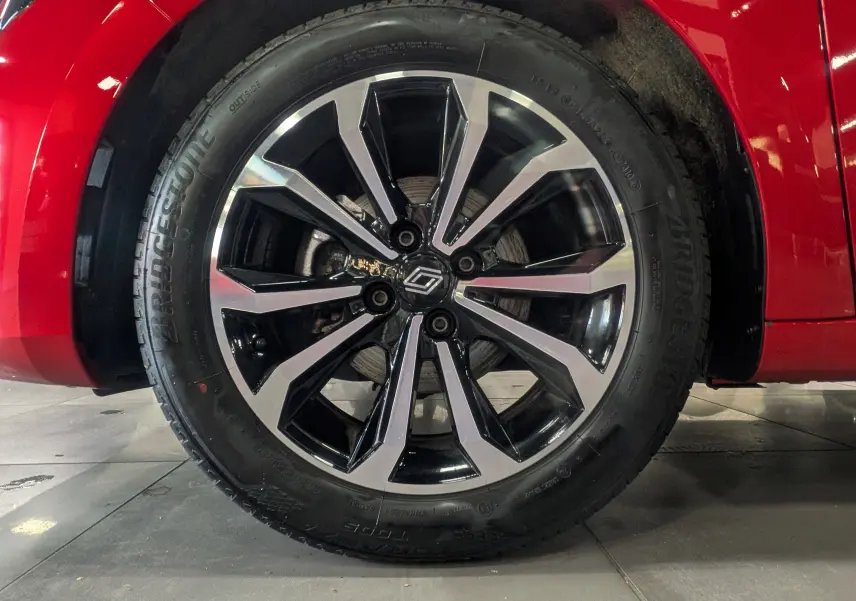 Gros plan sur la roue avant gauche de la Renault Clio V Rouge Flamme avec jante alliage bicolore au design moderne.