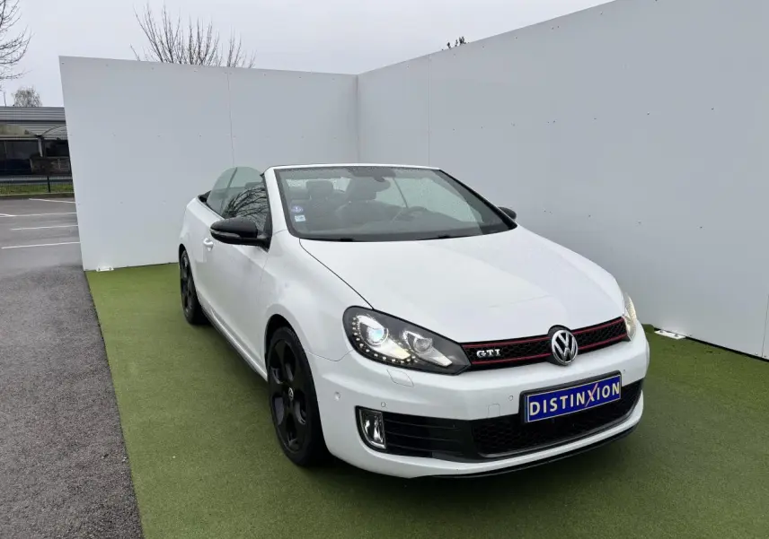 Volkswagen Golf VI Cabriolet blanc vue 3/4 avant avec jantes noires et calandre GTI rouge
