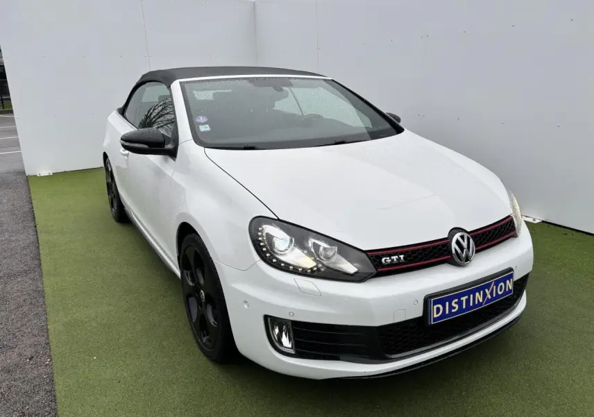 Volkswagen Golf VI Cabriolet blanc vue 3/4 avant avec toit souple noir et jantes alliage noires.