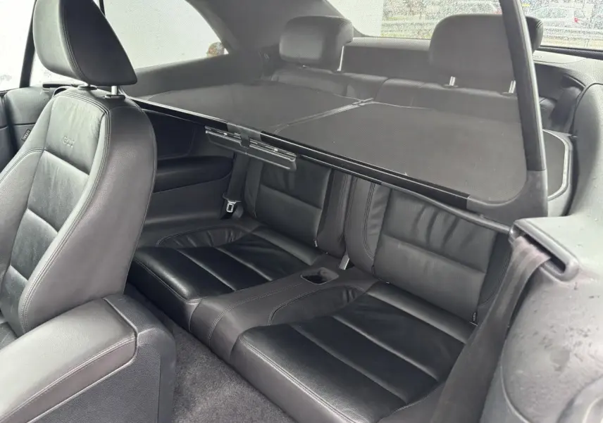 Vue intérieure côté arrière droit de la Volkswagen Golf VI Cabriolet avec sièges en cuir noir et filet anti-remous.