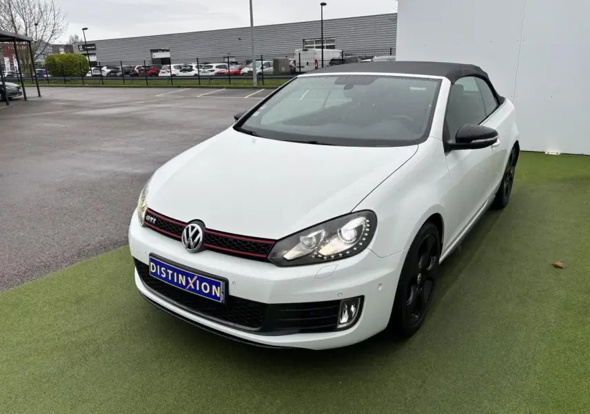 Volkswagen Golf VI Cabriolet blanc vue 3/4 avant droit avec toit souple noir et jantes noires.