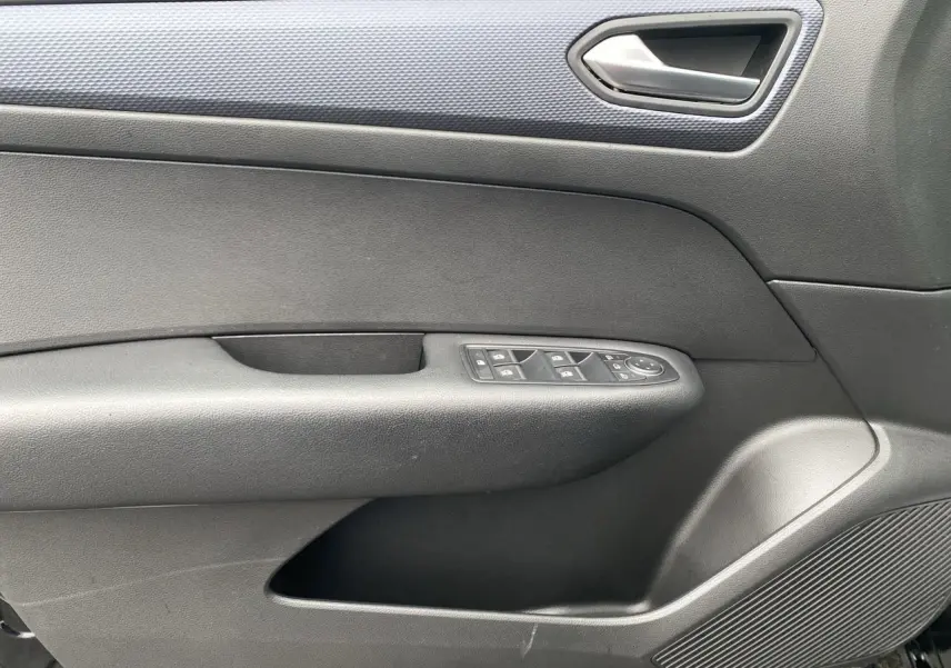 Intérieur de la porte côté gauche d’une Renault Arkana noire 2024, avec commandes de vitres et poignée argentée.
