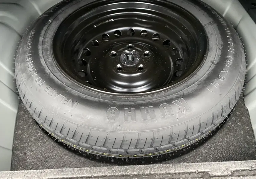 Gros plan sur la roue de secours noire en acier du Renault Arkana TCE 140 Essence 2024, logée dans le coffre.