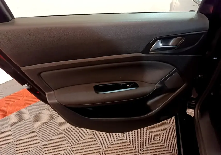 Vue intérieure de la porte avant gauche noire d'une Peugeot 308 2020, avec poignée et commande de vitre visible.