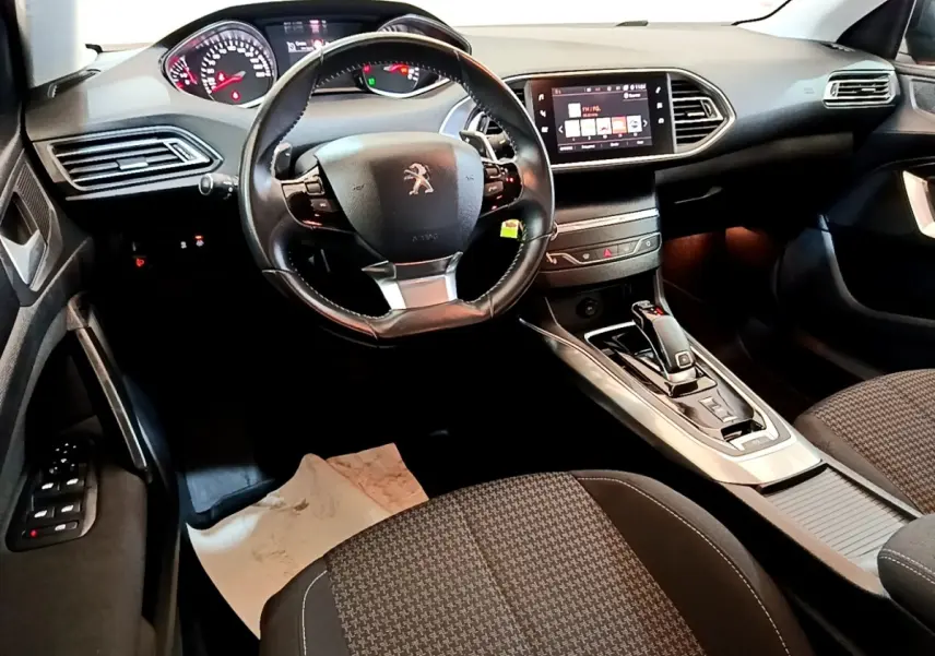 Intérieur noir de la Peugeot 308 2020, vue côté conducteur montrant volant cuir, tableau de bord digital et écran tactile central.