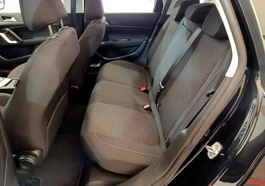 Vue intérieure côté droit montrant la banquette arrière grise et les sièges avant d'une Peugeot 308 noire de 2020.