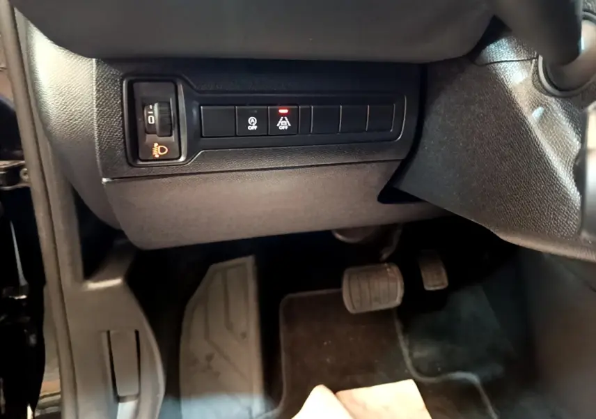 Vue intérieure côté conducteur de la Peugeot 308 noire, montrant les commandes d'éclairage et pédales au plancher.