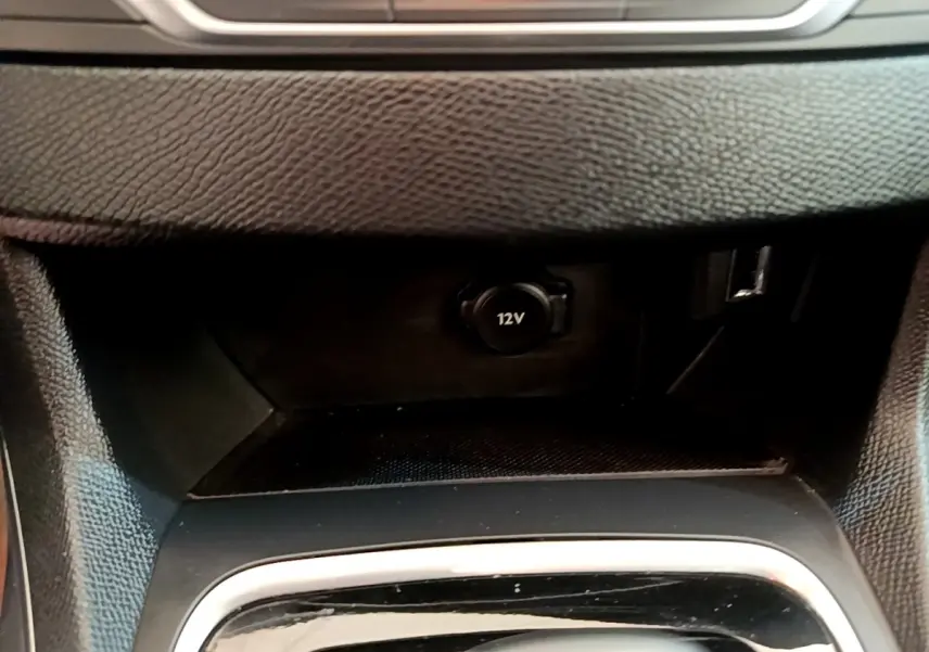 Gros plan sur la prise 12V et port USB dans la console centrale noire d'une Peugeot 308 2020.