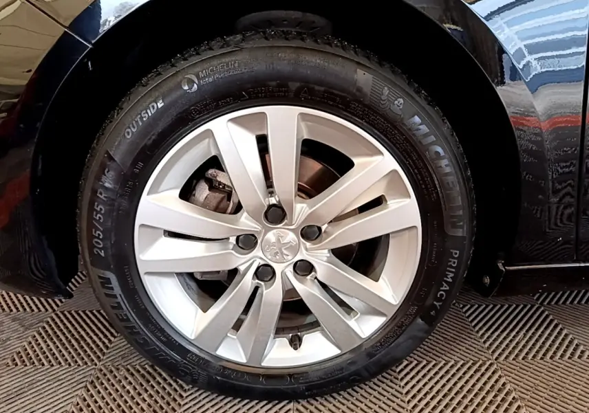 Vue rapprochée sur la roue arrière droite d’une Peugeot 308 noire, avec reflet sur la carrosserie brillante.