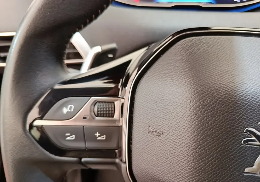 Gros plan sur le volant cuir noir de la Peugeot 3008 2022 avec commandes multifonctions à gauche.