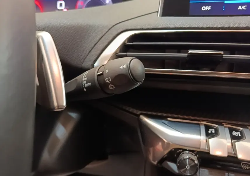 Gros plan sur la commande d’essuie-glace à gauche du volant dans l’habitacle du Peugeot 3008 noir 2022.