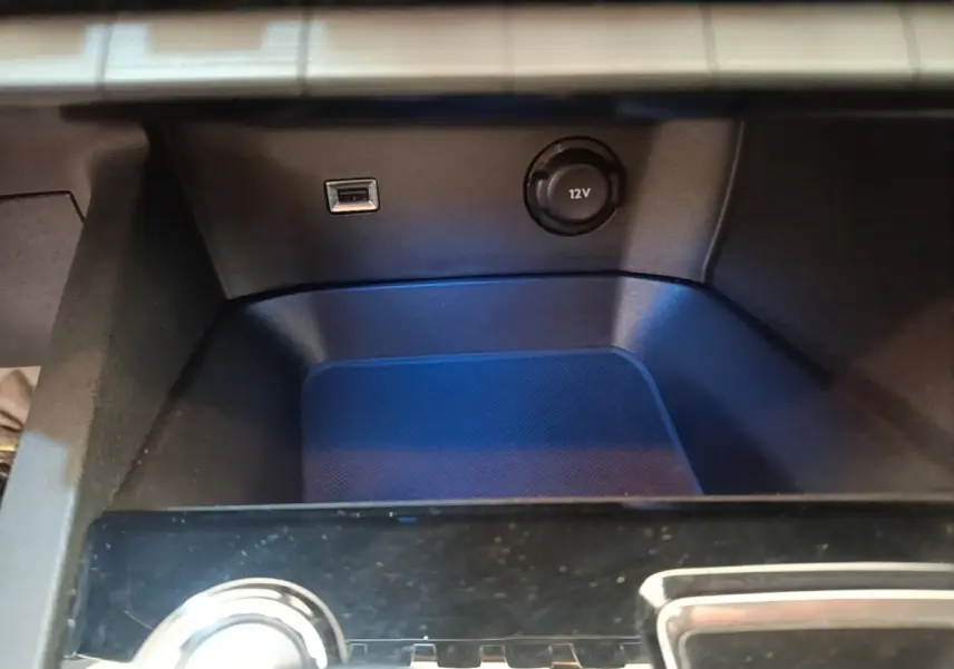 Gros plan sur la console centrale noire du Peugeot 3008 avec prise USB et prise 12V visible.