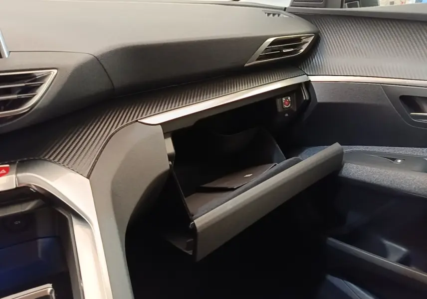 Vue intérieure côté passager du Peugeot 3008 2022 noir, avec boîte à gants ouverte et tableau de bord texturé.