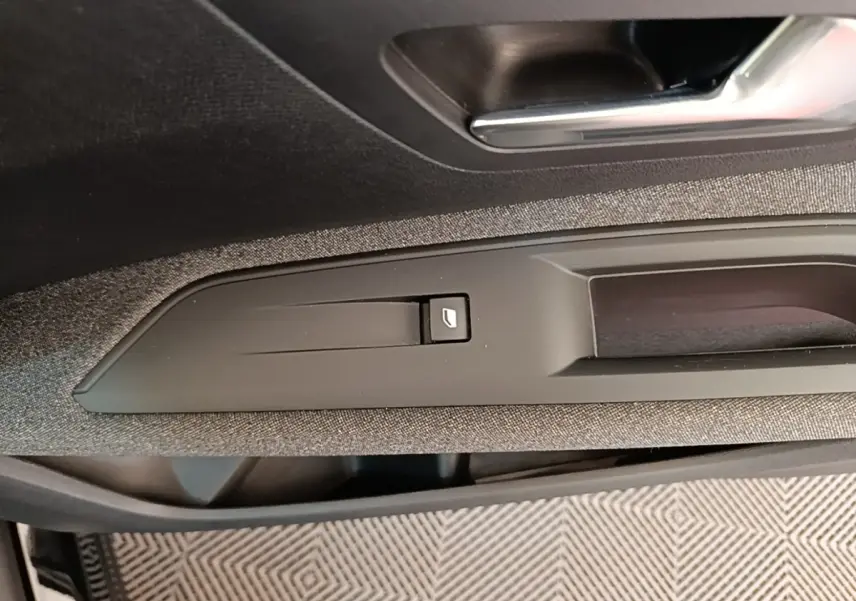 Détail de la commande d'ouverture de coffre sur la porte intérieure d'un Peugeot 3008 noir, vue rapprochée.