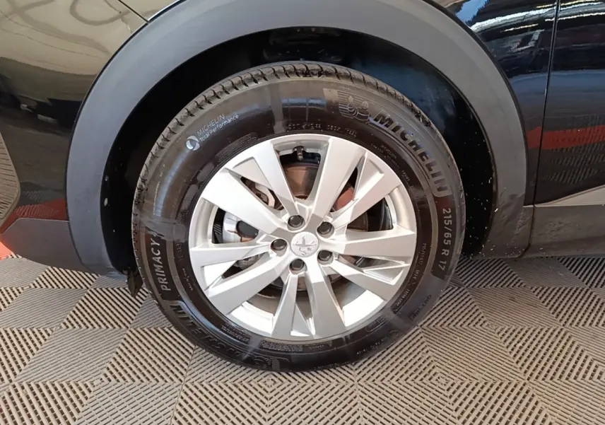 Gros plan sur la roue arrière droite d’un Peugeot 3008 noir, avec jante alliage argent et pneu Michelin.