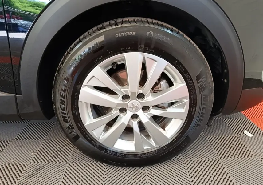 Gros plan sur la roue avant gauche du Peugeot 3008 noir, mettant en valeur la jante alliage et le pneu Michelin.