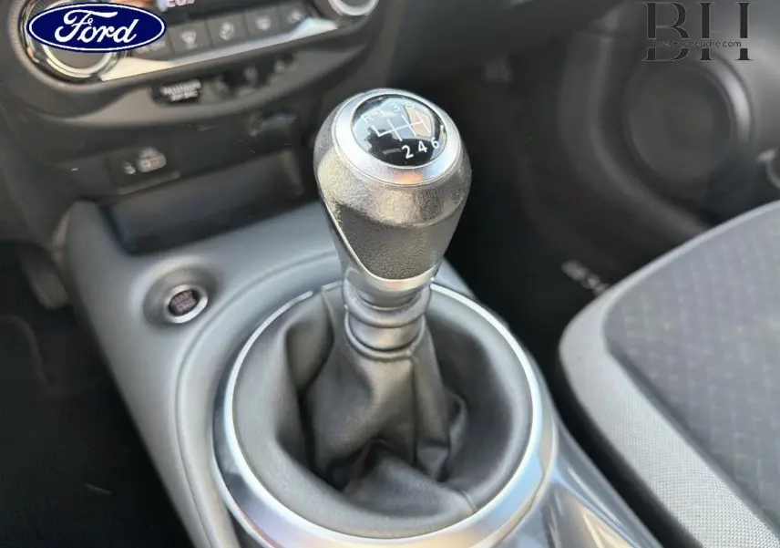 Gros plan sur le levier de vitesses manuel noir et argenté dans l’habitacle d’un Nissan Juke, siège gris visible à droite.