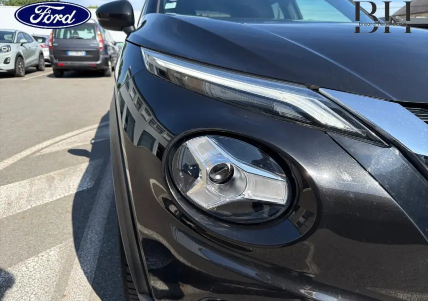 Gros plan sur le phare avant droit du Nissan Juke noir métallisé, mettant en valeur son design distinctif et moderne.
