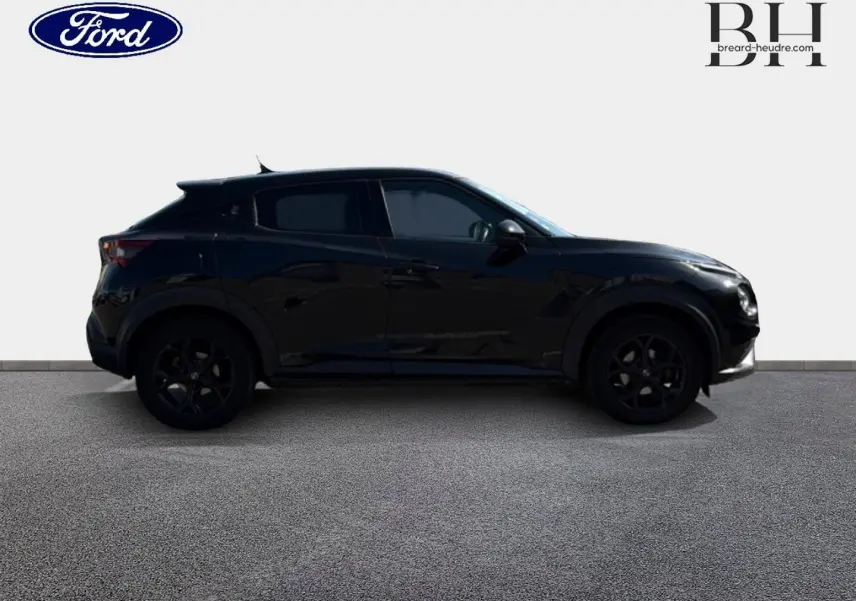 Vue de profil côté gauche d'un Nissan Juke noir métallisé avec jantes noires sur fond clair.