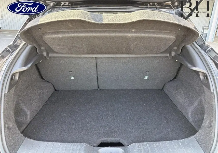 Coffre ouvert vu de l'arrière d'un Nissan Juke noir métallisé, montrant l'espace de chargement vide et la trappe de sol.