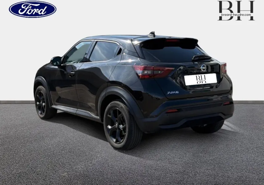 Vue 3/4 arrière d’un Nissan Juke noir métallisé avec jantes noires et vitres teintées sur un sol gris.