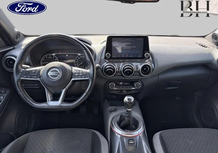 Vue intérieure avant du Nissan Juke 2020, tableau de bord noir avec écran tactile et levier de vitesse manuel.