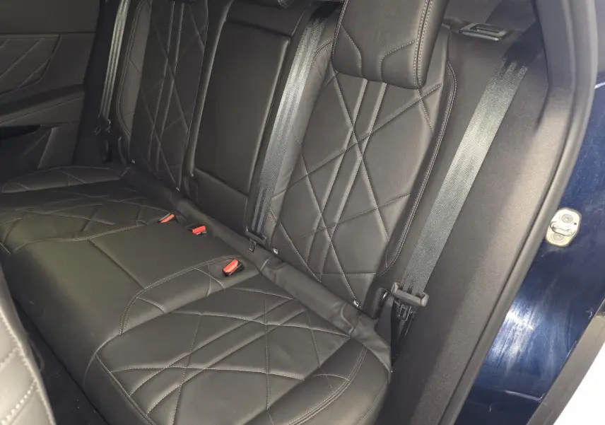 Vue rapprochée de la banquette arrière en cuir noir avec surpiqûres, porte arrière bleu visible sur le côté droit.