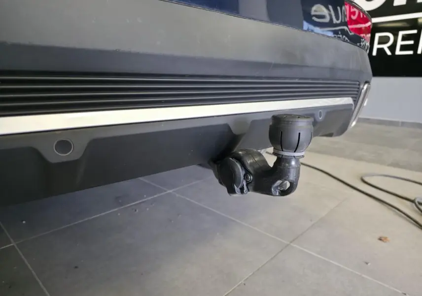 Gros plan sur l'attelage escamotable noir sous le pare-chocs arrière bleu métallisé du DS7 Crossback 2024.