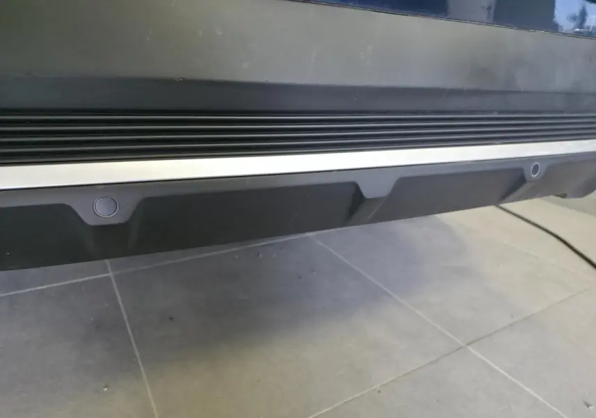 Gros plan sur le bas de caisse arrière noir et chrome du DS7 Crossback Bleu, montrant les capteurs de stationnement intégrés.