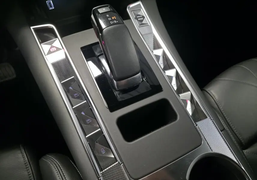 Vue rapprochée de la console centrale noire du DS7 Crossback 2024 avec levier de boîte auto et boutons argentés.
