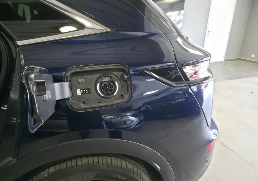 Vue arrière côté gauche du DS7 Crossback bleu avec trappe de recharge hybride ouverte et feux arrière distinctifs.