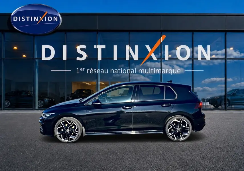 Profil droit d'une Volkswagen Golf noire 2026 R-Line avec jantes sport devant une vitrine Distinxion.