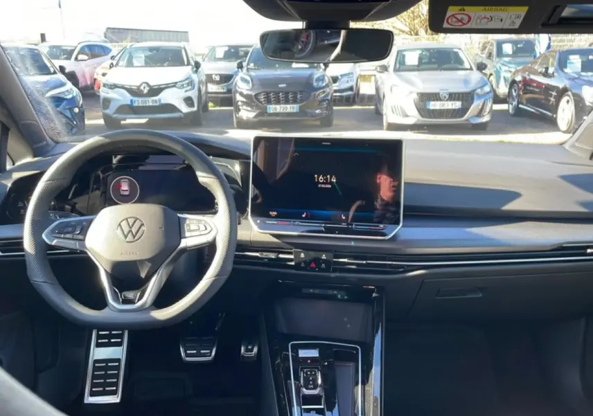Vue intérieure avant de la Volkswagen Golf noire 2026, volant cuir multifonction et écran tactile central lumineux.