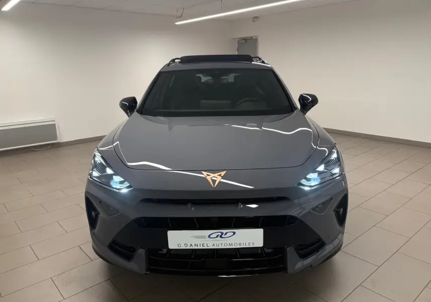 Vue frontale d'un CUPRA Formentor 2025 gris graphène avec phares allumés et toit ouvrant panoramique visible.