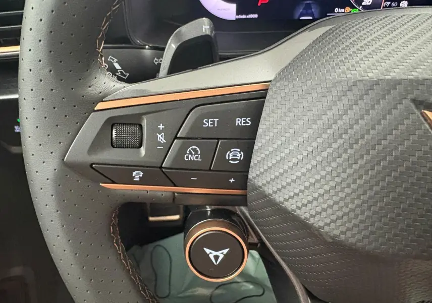 Gros plan sur le volant perforé du CUPRA Formentor 2025 avec commandes intégrées et logo cuivré distinctif.