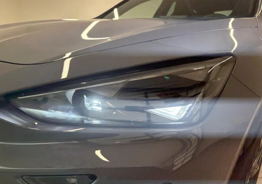 Gros plan sur le phare avant droit du CUPRA Formentor 2025 gris graphène avec peinture spéciale et toit ouvrant panoramique visible.