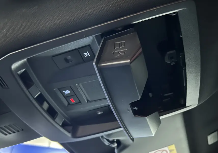 Gros plan sur le compartiment à lunettes ouvert et les commandes du plafonnier du Peugeot 3008 Bleu Ingaro 2025.