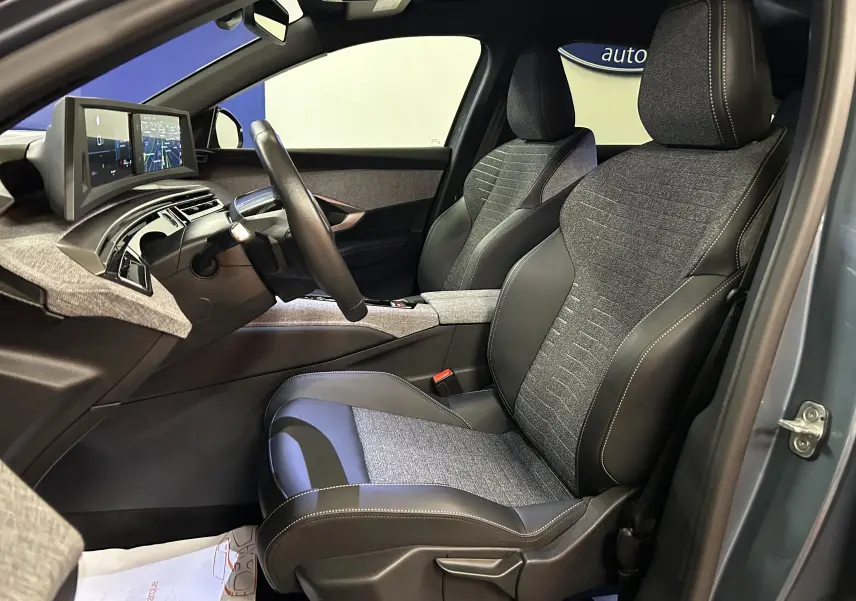 Vue intérieure côté conducteur du Peugeot 3008 hybride 2025 avec sièges tissu et cuir gris et tableau de bord digital.