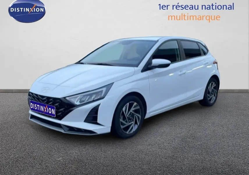 Vue 3/4 avant droite d'une Hyundai i20 blanche Atlas 2025 avec jantes alliage et calandre noire distinctive.
