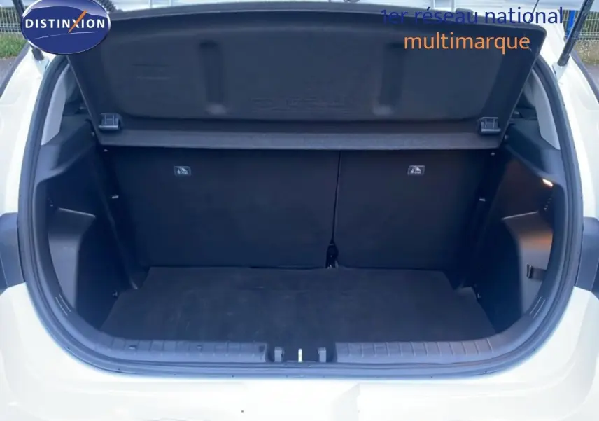 Coffre ouvert vu de l'arrière d'une Hyundai i20 blanc atlas, montrant l'espace de chargement vide et la trappe de coffre.