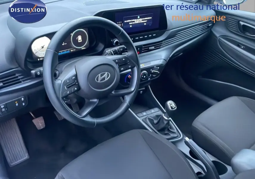 Vue intérieure côté conducteur de la Hyundai i20 2025, tableau de bord moderne avec volant cuir et écran central tactile.