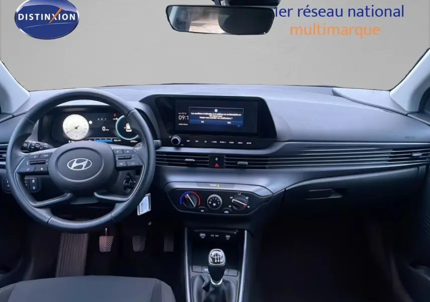 Vue intérieure avant de la Hyundai i20 blanche Atlas 2025, tableau de bord moderne avec écran tactile et boîte manuelle.